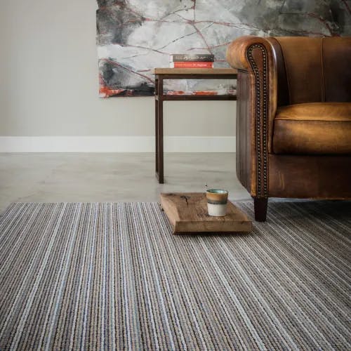 Masai Ocean striped wool rug in living room with leather chair